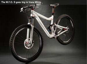 Niner W.F.O. 9: A white mountain bike displayed against a dark background, showcasing its sleek design and large tires. The bike features a dual suspension system and prominent branding elements. The image highlights the bike's advanced components and sporty aesthetic.