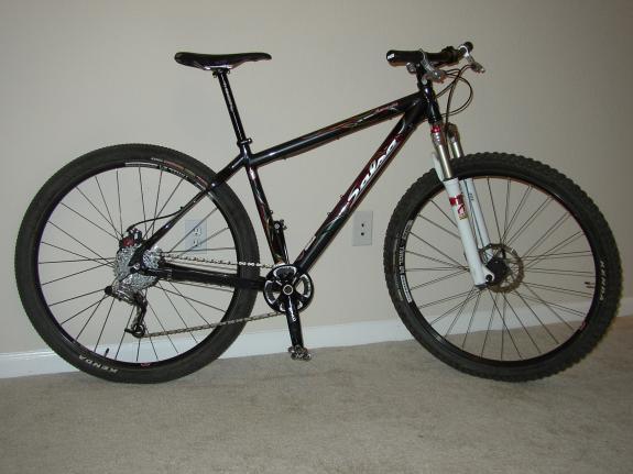 Salsa Mamasita: A black mountain bike with red and white accents, featuring thick tires, a front suspension fork, and a lightweight frame, standing on a carpeted surface against a plain wall.