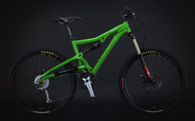Santa Cruz Heckler: A bright green mountain bike with a lightweight frame, featuring front suspension, disc brakes, and rugged tires. The bike is set against a dark background, highlighting its design and components.