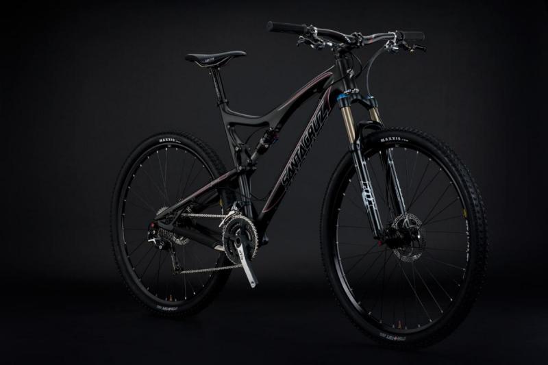 Santa Cruz Tallboy Carbon: Alt text: A black mountain bike with a glossy finish, featuring a prominent logo on the frame. The bike has front suspension and rugged tires, displayed against a dark background.