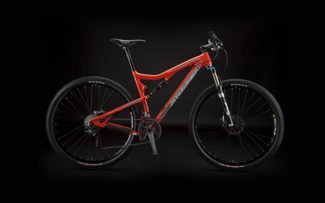 Santa Cruz Tallboy: A modern mountain bike with a bright red frame, featuring dual suspension, wide tires, and a sleek design. The bike is positioned against a dark background, highlighting its features such as the handlebars, seat, and suspension fork.
