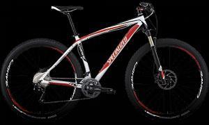 Specialized Carve Pro: Mountain bike with a sleek design featuring a white and red frame, black tires, and modern components, set against a dark background.