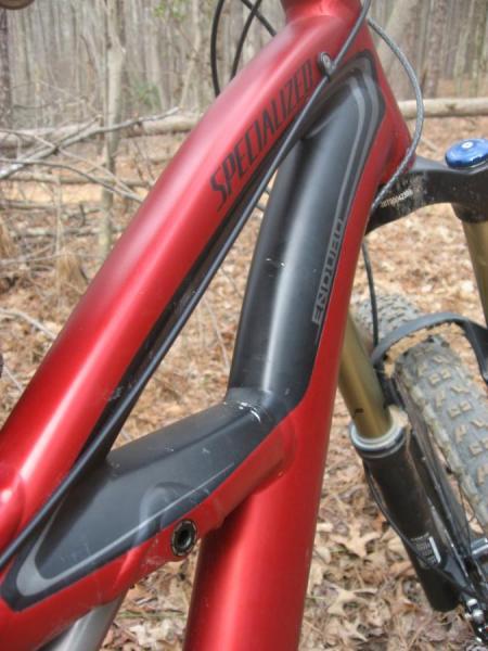 Specialized Enduro Expert: Alt text: Close-up view of a red Specialized mountain bike frame, showcasing the sleek design with black accents, set against a natural background of brown leaves and trees.
