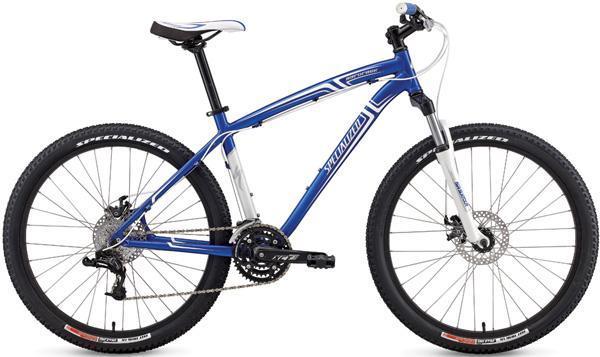 Specialized Hardrock Disc: A blue and white mountain bike with a lightweight frame, featuring front disc brakes, knobby tires, and a gear system suitable for off-road riding. The bike is positioned against a plain background, showcasing its design and components clearly.