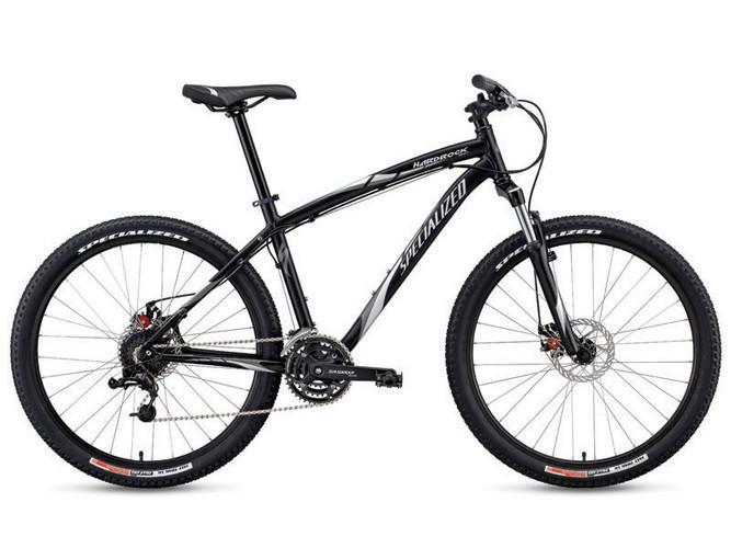 Specialized Hardrock Disc: A black mountain bike with a lightweight frame, featuring thick tires and disc brakes, designed for off-road terrain. The bike has a simple gear system and a comfortable saddle, suitable for outdoor cycling adventures.
