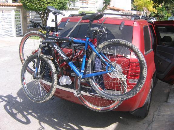 Specialized Hardrock Sport Disc: Alt text: Two bicycles mounted on the back of a red SUV, with one bike in blue and black and the other in green and black, parked on a street.
