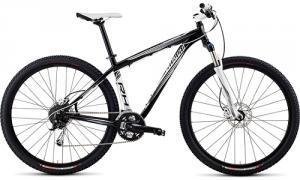 Specialized Rockhopper Comp 29: A black and white mountain bike with thick tires, a front suspension fork, and a sleek frame design, positioned on a white background.