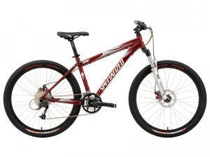 Specialized Rockhopper Comp Disc: A red mountain bike featuring a lightweight frame, thick tires, and a front suspension fork, designed for off-road trails. The bike includes disc brakes and a gear shifter, showcasing a modern design suitable for cycling enthusiasts.
