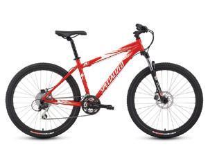 Specialized Rockhopper Disc: A red mountain bike with a sleek design, featuring a sturdy frame, thick tires, and disc brakes. The bike has a comfortable seat and is positioned on a white background, showcasing its sporty aesthetic.