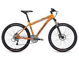 Specialized Rockhopper Pro Disc: A bright orange mountain bike with durable tires, a sturdy frame, and disc brakes, positioned on a white background.