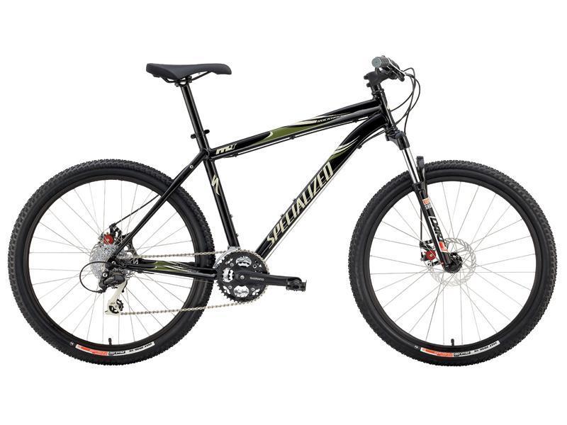 Specialized Rockhopper: Mountain bike with a black frame, featuring green accents and a logo. It has wide tires, a front suspension fork, and multiple gears, designed for off-road terrain.