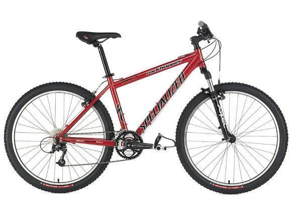 Specialized Rockhopper: A red mountain bike with a sturdy frame, wide tires, and front suspension, designed for off-road cycling. The bike features a black handlebar, a seat, and gear components, showcasing the brand "Specialized." The overall design indicates it is built for durability and performance on various terrains.