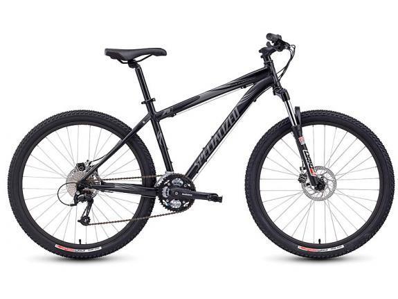 Specialized Rockhopper: A black mountain bike with wide tires, featuring a durable frame and disc brakes, positioned on a white background. The bike is equipped with a gear system and prominently displays the "Specialized" brand logo on the frame.