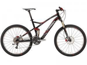 Specialized S-Works Stumpjumper FSR: Mountain bike with a sleek black and red design, featuring thick tires, a dual suspension system, and multiple gears. The bike is positioned upright, showcasing its frame and components.