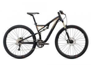 Specialized Stumpjumper FSR Comp 29: A black and gold mountain bike with a sturdy frame, front suspension, and knobby tires, positioned against a plain white background.