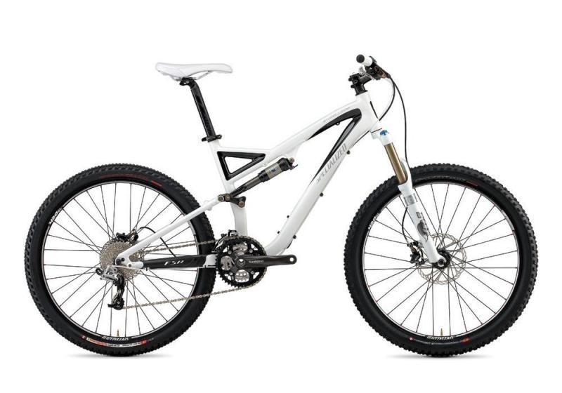 Specialized Stumpjumper FSR: A white mountain bike with a lightweight frame, front suspension, and knobby tires, positioned on a plain background. The bike features disc brakes, a multi-gear system, and a sleek design tailored for trail riding.