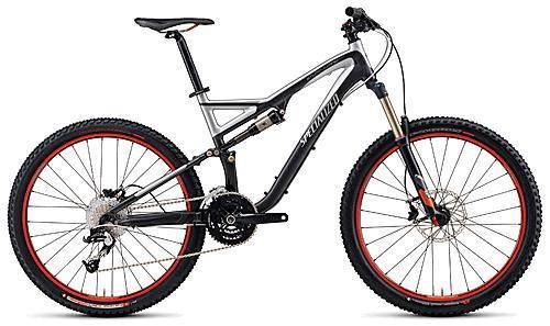 Specialized Stumpjumper: Mountain bike with a sleek black and silver design, featuring red accents on the wheels and tires. It has front suspension, a dual chainring crankset, and a height-adjustable seat.