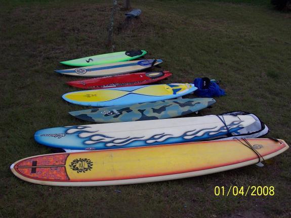 Specialized Stumpjumper: A row of surfboards of various colors and designs laid out on green grass, with a blue towel and a tree in the background. The surfboards range from bright green and red to blue with camo patterns and yellow with flame designs. The date at the bottom of the image indicates it was taken on January 4, 2008.