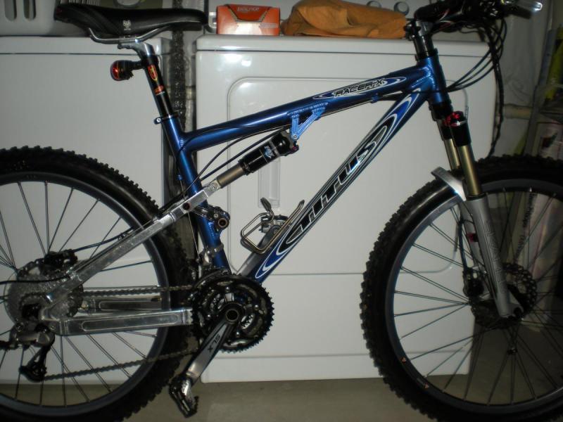 Titus Racer X: A blue mountain bike with a silver frame and black tires, positioned near a white washing machine.