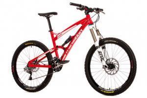 Transition Covert: A bright red mountain bike with a lightweight frame, front suspension, and wide tires designed for off-road cycling. The bike features disc brakes, a comfortable seat, and a geared drivetrain ideal for various terrains.