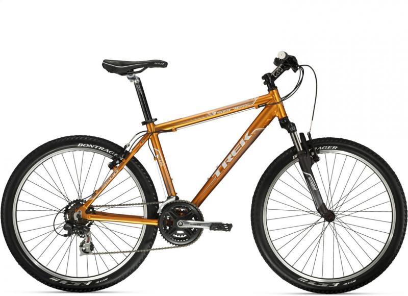 Trek 3500: Alt tag: A Trek mountain bike with an orange frame, featuring thick tires and a front suspension fork. The bike is shown from the side, highlighting its design and components.