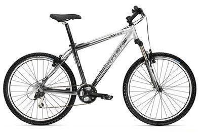 Trek 4300: Mountain bike with a silver frame, black tires, and a simple gear mechanism, positioned against a white background.