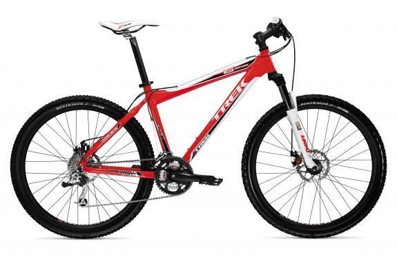 Trek 6000: A red and white mountain bike with a sleek design, featuring front suspension, disc brakes, and knobby tires suitable for off-road terrain. The bike is stylishly designed with the brand name visible on the frame.