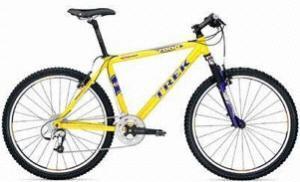 A bright yellow mountain bike with black and purple accents, featuring wide tires, a durable frame, and a multi-gear system.