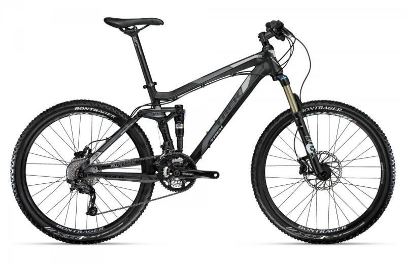 Trek Fuel EX 8: Alt text: A black and gray mountain bike with a lightweight frame, front suspension fork, and disc brakes, positioned against a plain white background. The bike features wide tires and a Shimano gear system.
