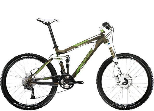 Trek Fuel EX 8: A modern mountain bike with a sleek design featuring a brown frame with green accents, front suspension fork, and wide tires, positioned on a white background.