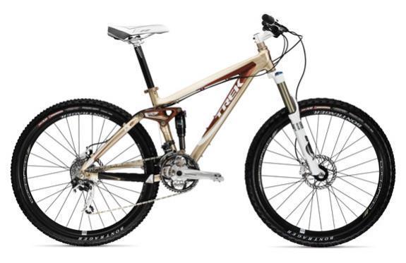 Trek Fuel EX 8: A modern mountain bike with a light frame featuring a combination of beige and brown colors. The bike includes front suspension forks, disc brakes, and wide tires designed for off-road terrain.