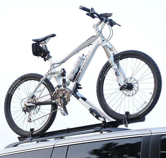 Trek Fuel EX 8: Alt text: A white mountain bike is securely mounted on the roof rack of a vehicle, showcasing its wheels, gears, and handlebars against a clear sky.
