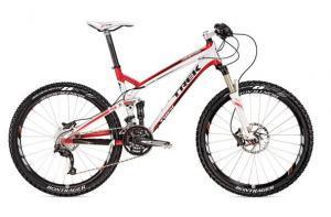 Trek Top Fuel 8: A red and white mountain bike with a lightweight aluminum frame, equipped with disc brakes, wide tires, and a front suspension fork, positioned at an angle to showcase its design.