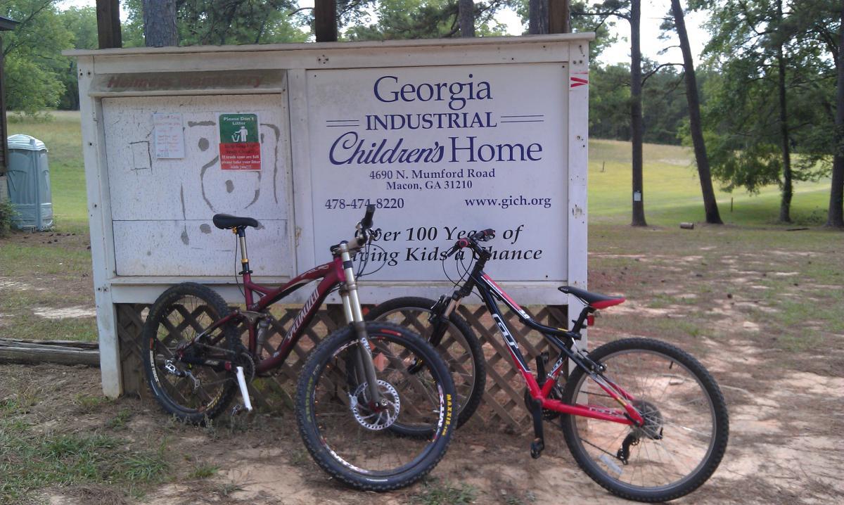 Two mountain bikes are leaning against a sign for the Georgia Industrial Children