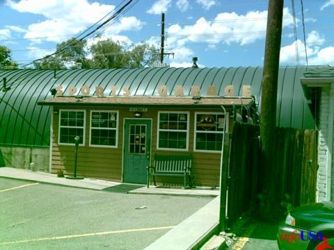 A metal-roofed building with a wooden facade, featuring large windows and a door, labeled "Ford
