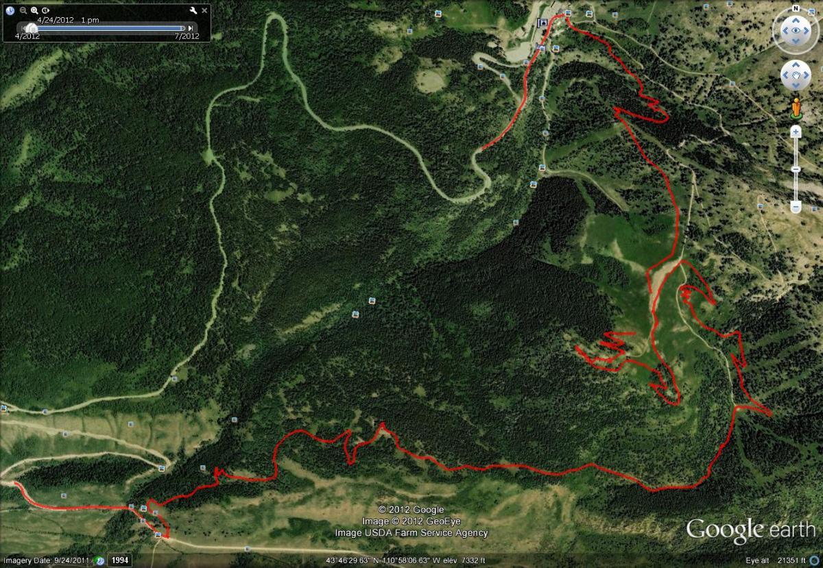 A satellite image showing a map of forested terrain with winding paths marked in red. The topography features various elevations and areas of dense vegetation, along with a few clearings and road access points. The map includes geographic coordinates and a timestamp indicating the imagery date. Mill Creek mountain bike trail.
