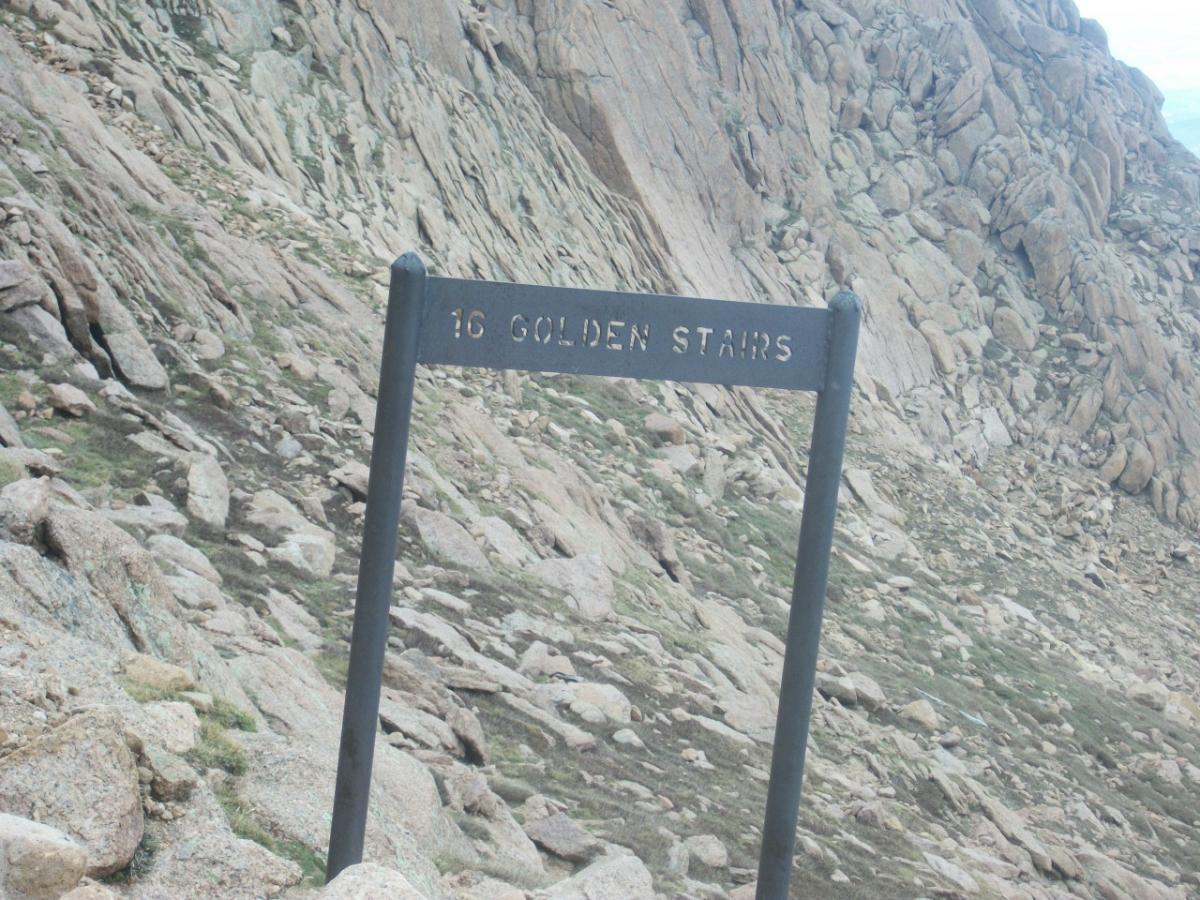 Sign marking "16 Golden Stairs" on a rocky mountain trail, surrounded by boulders and rugged terrain. Barr Trail / Pikes Peak mountain bike trail.