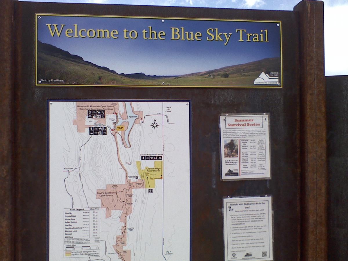 Welcome sign for the Blue Sky Trail featuring a map of the trail system and information on safety and events. The sign includes details about nearby areas, trail lengths, and a warning about local wildlife. Blue Sky mountain bike trail.