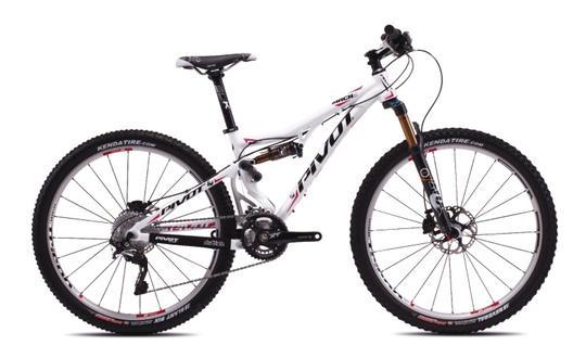 Pivot Mach 4: Alt text: A white mountain bike with pink and black accents, featuring disc brakes, thick tires, and a prominent "Pivot" logo on the frame. The bike is viewed from the side, showcasing its design and components.