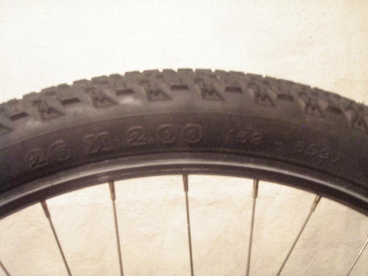 Michelin XCR Dry2: Close-up view of a bicycle tire showing the tread pattern and sidewall markings, specifically reading "26 x 2.00." The focus is on the tire against a plain background.