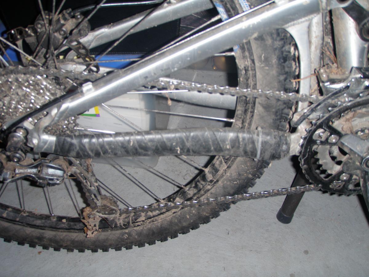 Specialized Specialized Specialized Standard Tube 26"x1.5/2.2 (Presta): Close-up image of a mountain bike's drivetrain, showcasing the gears, chain, and rear wheel. The bike frame is partially visible, along with dirt and debris on the components, indicating some use on rough terrain. The background is slightly blurred, focusing on the bike's mechanical details.