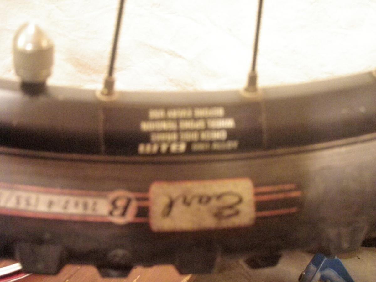 Bontrager Big Earl Folding: A close-up view of a bicycle rim with a partially visible tire label. The rim features a metallic valve stem and printed specifications on the side. Some markings, including a handwritten number on a sticker, are also visible. The background appears blurred, focusing on the rim details.