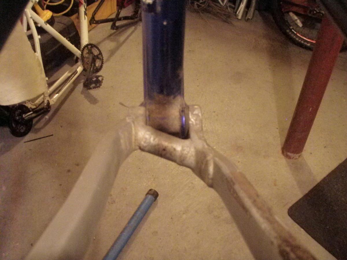 Specialized FSR: Image showing a close-up view of a bicycle frame's bottom bracket area, highlighting welds and paint details. The background includes parts of other bicycles and tools, indicating a workshop environment.