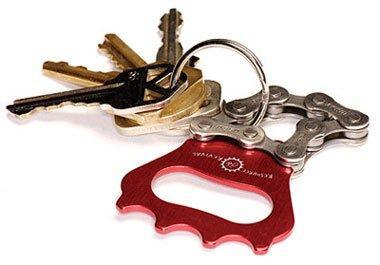 Resource Revival Recycled Bicycle Chain Key Chain Bottle Opener: A collection of keys attached to a keyring, featuring a distinctive red bottle opener shaped like a bike chain link among the keys.