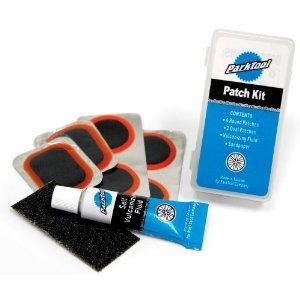 Park VP-1 Vulcanizing Patch Kit: A bicycle patch kit containing several round patches with orange borders, a tube of adhesive, and a piece of sandpaper, all housed in a clear plastic case.