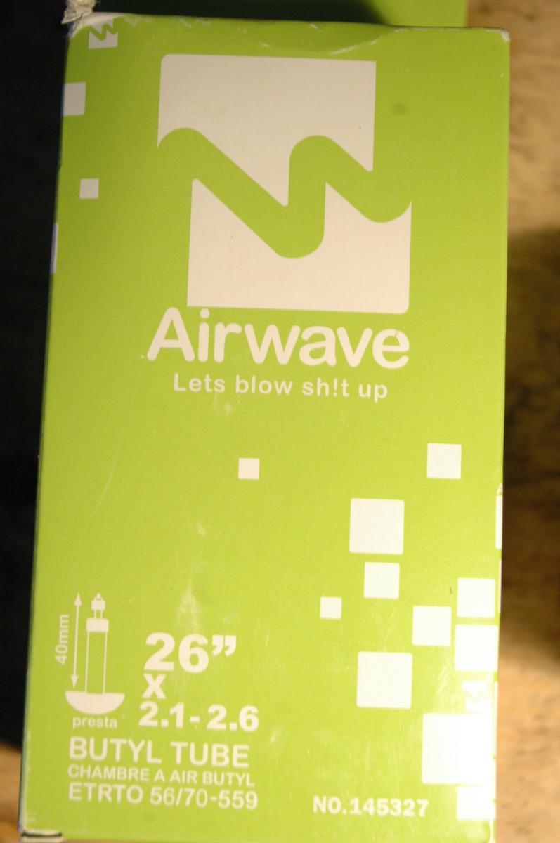 Airwave MTB Tube: A green packaging box for a bicycle butyl tube, featuring the text "Airwave" and the slogan "Let's blow sh!t up." The box displays specifications including the size (26” x 2.1-2.6), an illustration of a presta valve, and the product code.
