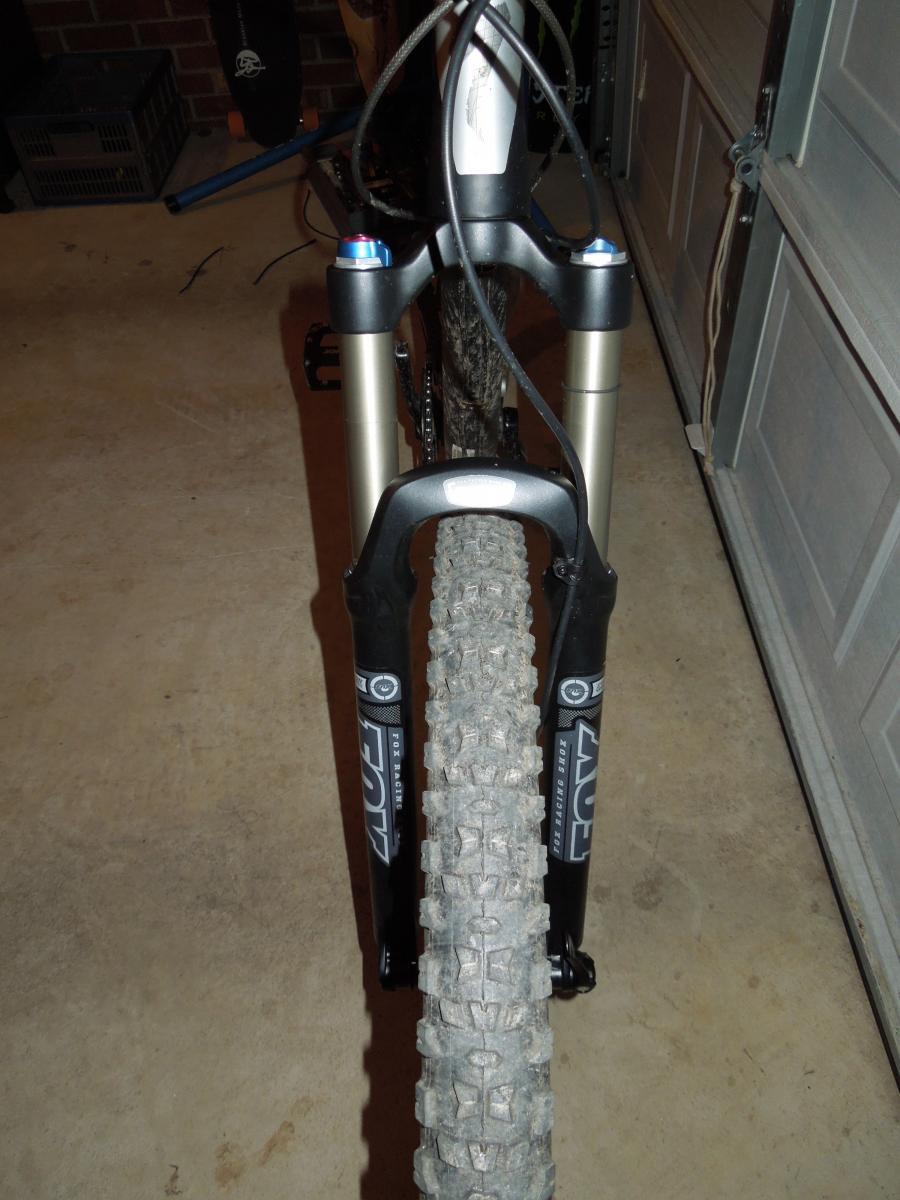 Jagwire Ripcord Brake Kits: Alt text: A close-up view of a mountain bike's front fork and tire, showcasing the suspension components and knobby tire tread on a concrete floor in a garage setting.