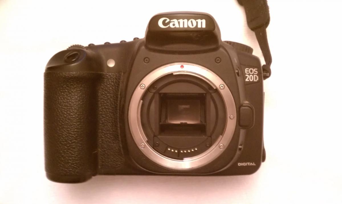 Canon 20D: A Canon EOS 20D digital camera shown from the front, featuring a large lens mount with no lens attached, and a textured grip for handling. The camera body has a black finish with the brand name "Canon" prominently displayed on the top.