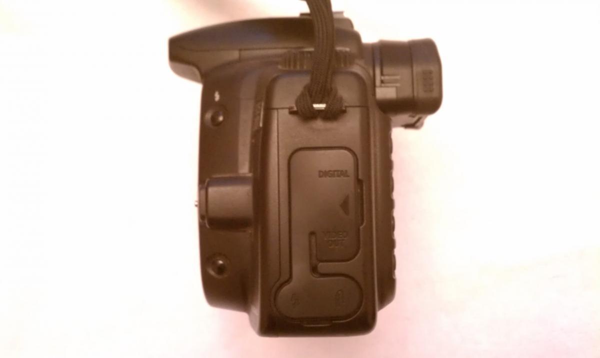Canon 20D: Digital camera viewed from above, highlighting the top and side controls, including a strap and various ports, against a white background.
