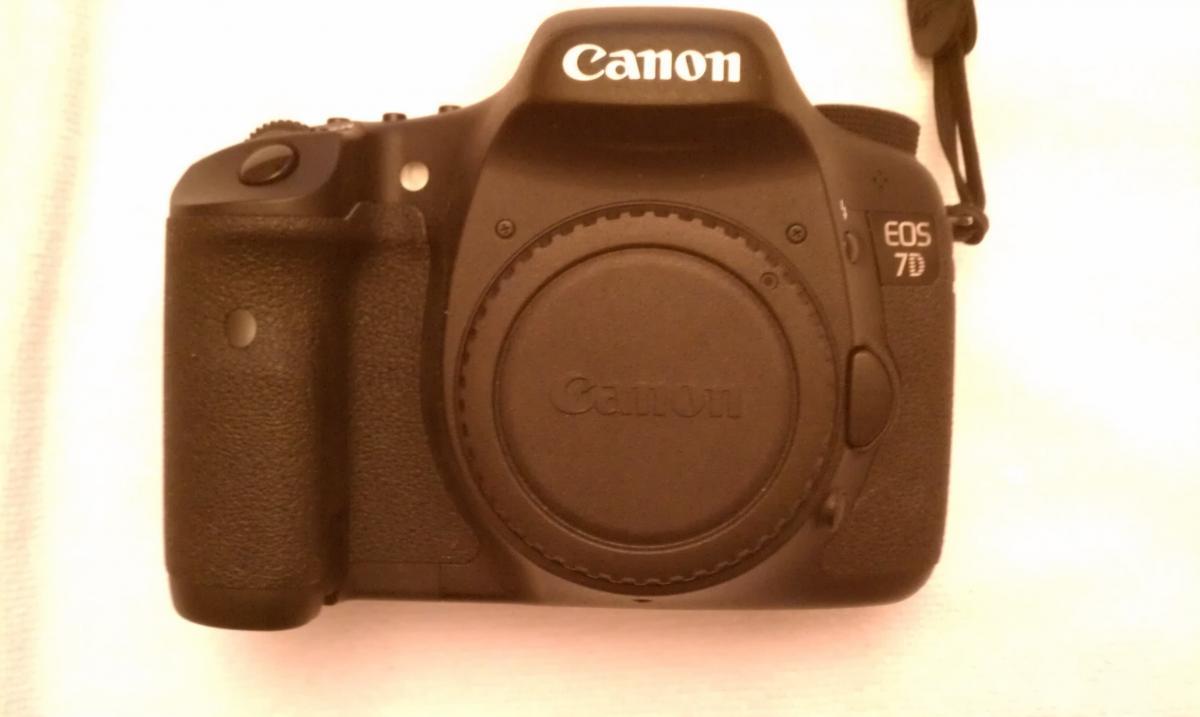 Canon 7D: A black Canon EOS 7D digital camera, viewed from the top, showing the lens cap in place and a textured grip on the side.